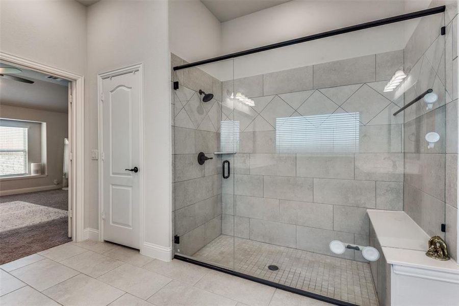 Bathroom featuring ceiling fan, an enclosed shower, and tile patterned floors