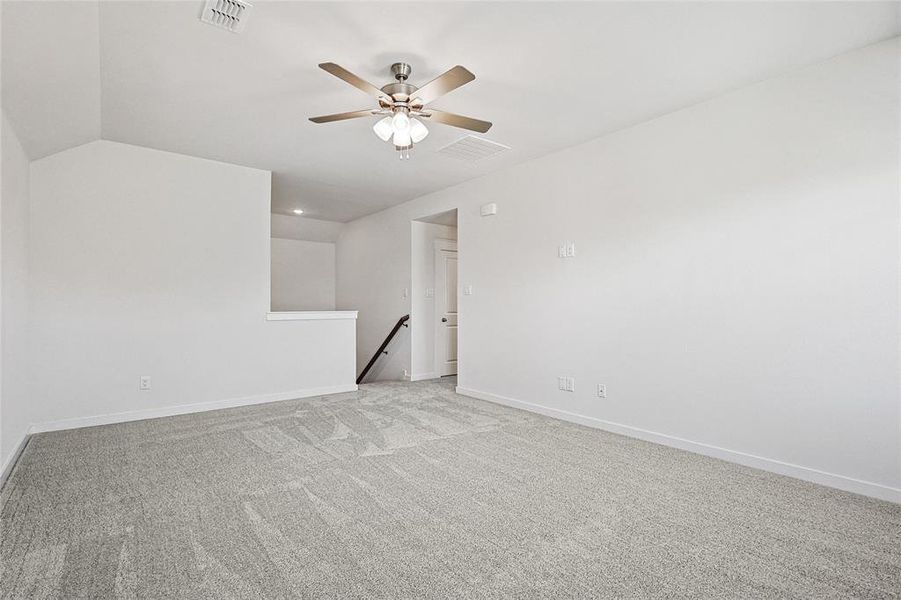 Carpeted spare room with ceiling fan and vaulted ceiling