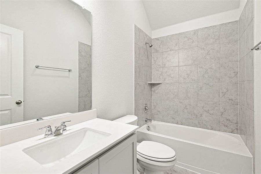 Full bathroom featuring toilet, vanity, lofted ceiling, and tiled shower / bath