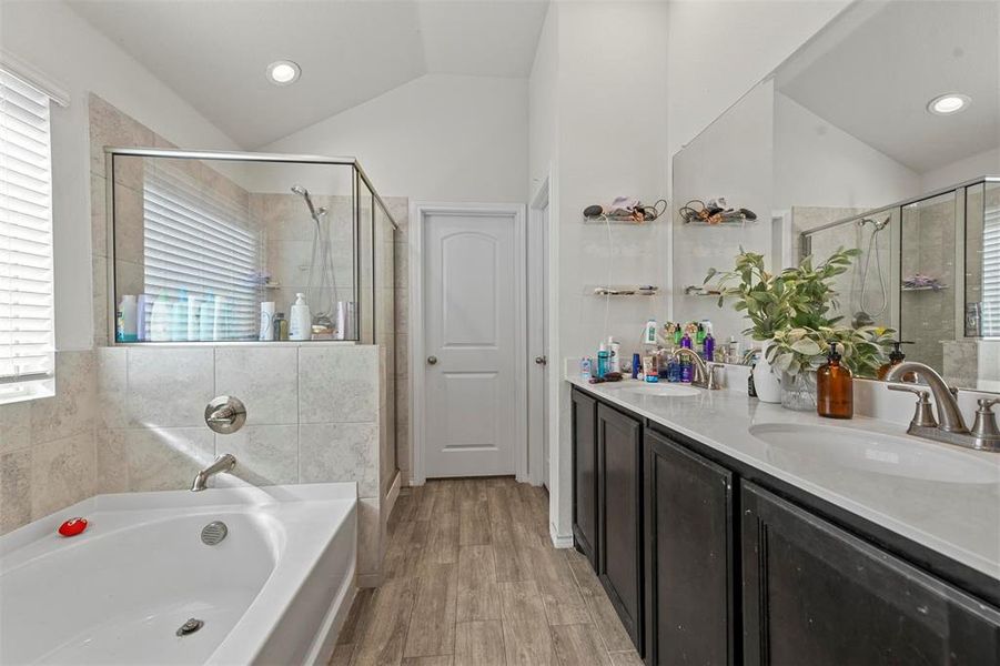 Bathroom featuring vanity, vaulted ceiling, plus walk in shower, and hardwood / wood-style flooring