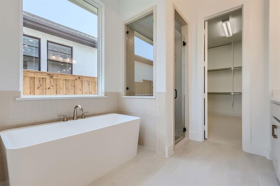 Bathroom with tile patterned floors, a wealth of natural light, and independent shower and bath