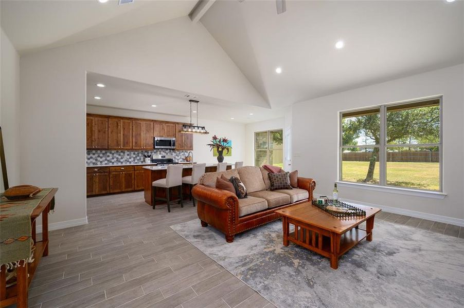 Living room featuring beamed ceiling, high vaulted ceiling, and light wood-type flooring