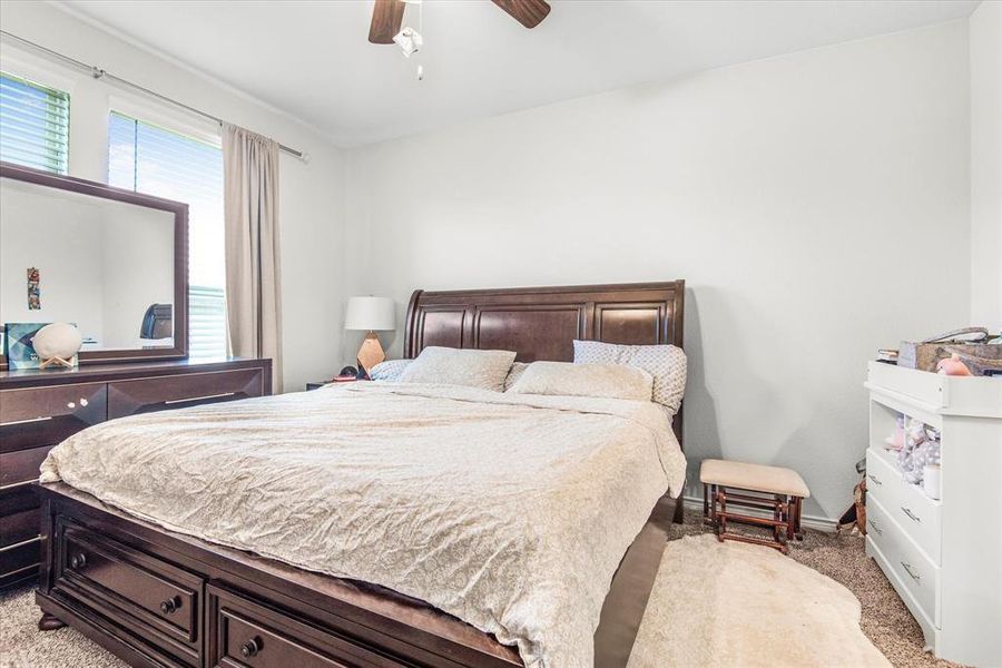 Carpeted bedroom featuring ceiling fan