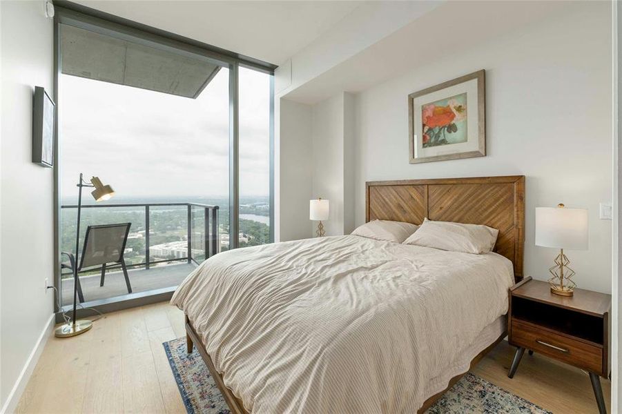 Primary bedroom with floor to ceiling windows with deck and views of downtown