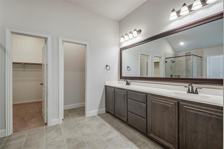 Bathroom featuring a shower with door, lofted ceiling, tile patterned flooring, and vanity