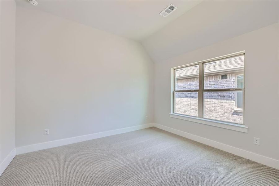 Spare room featuring carpet flooring and vaulted ceiling