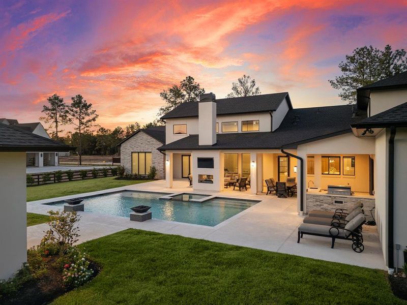 The back porch features a double-sided see-through fireplace with dual TVs, one facing the living area and the other facing the pool and spa.