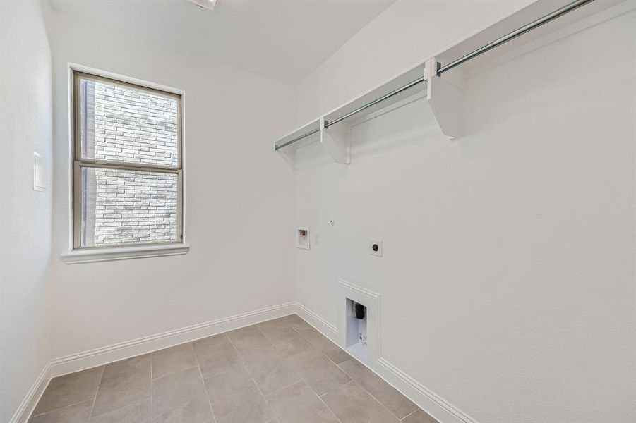 Clothes washing area with washer hookup, hookup for an electric dryer, light tile patterned floors, and gas dryer hookup