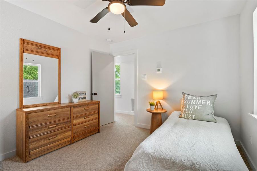 Carpeted bedroom with multiple windows and ceiling fan