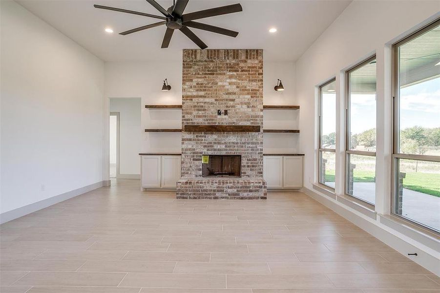 Unfurnished living room featuring a wealth of natural light, a brick fireplace, light hardwood / wood-style floors, and ceiling fan