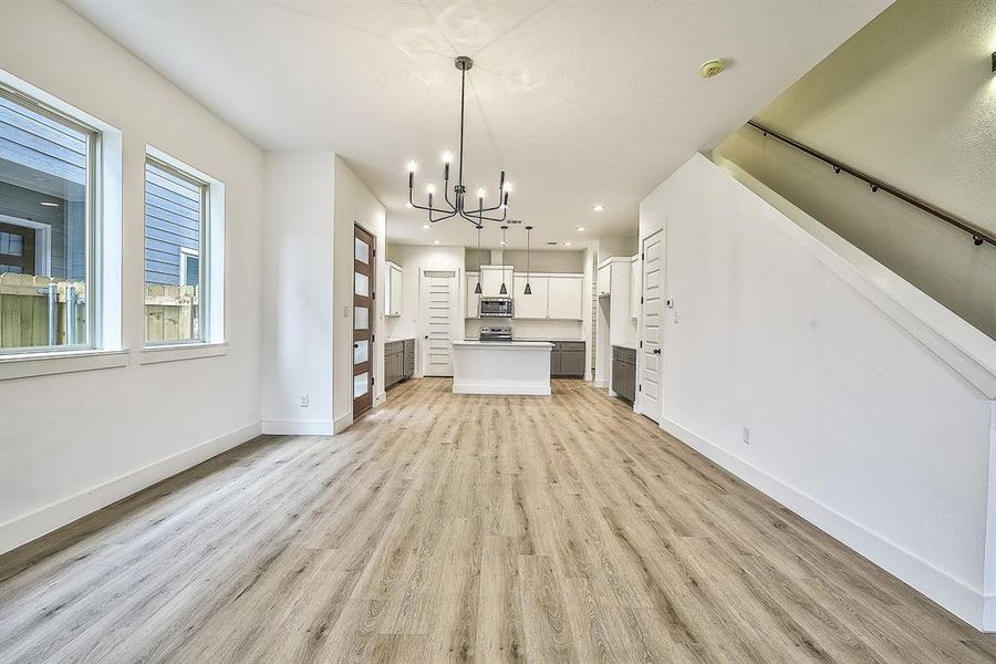 Unfurnished living room with light hardwood / wood-style floors and a notable chandelier