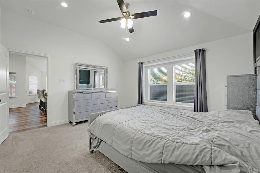 Carpeted bedroom with ceiling fan and lofted ceiling