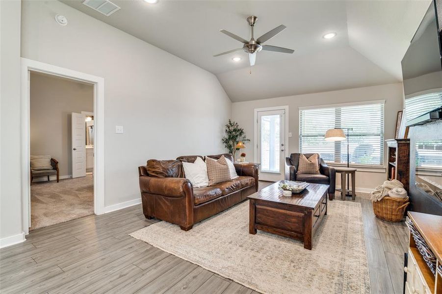 Living room with vaulted ceiling, ceiling fan, and light hardwood / wood-style flooring