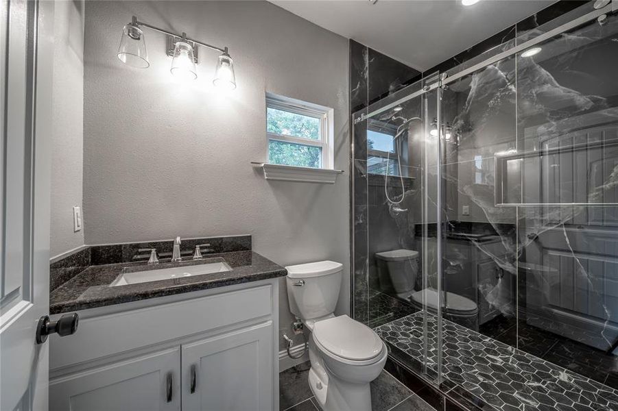 Bathroom with vanity, toilet, and a shower with shower door