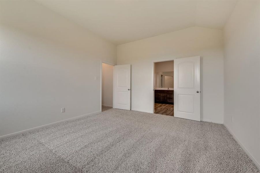 Carpeted empty room featuring lofted ceiling