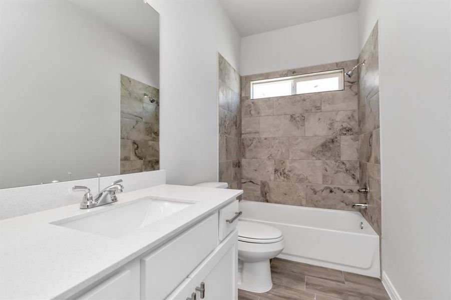 The guest bathroom in this home features sleek, modern finishes, including a stylish vanity with ample counter space and storage. The shower/tub combination is enhanced by elegant tile work, creating a spa-like atmosphere. The large mirror and contemporary lighting fixtures make the space feel bright and welcoming, providing a comfortable experience for guests and residents alike. **This image is from another Saratoga Home with similar floor plan and finishes, not the June floorplan.**