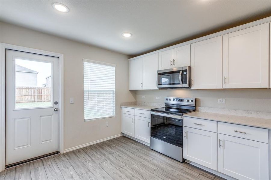 Kitchen featuring a wealth of natural light, appliances with stainless steel finishes, light hardwood / wood-style floors, and white cabinetry