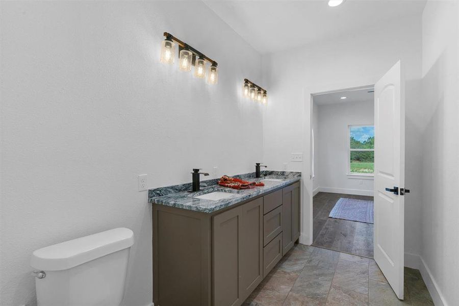 Bathroom with double sink vanity, toilet, and tile floors