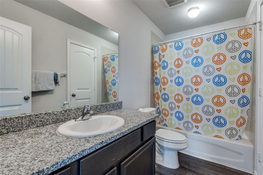 Full bathroom featuring vanity, toilet, hardwood / wood-style flooring, and shower / tub combo with curtain