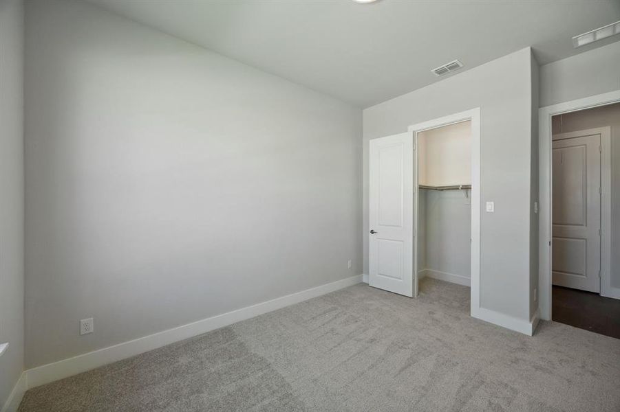 Unfurnished bedroom featuring a spacious closet, a closet, and carpet flooring