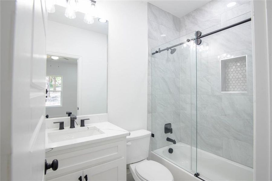 Full bathroom featuring toilet, tiled shower / bath combo, and vanity