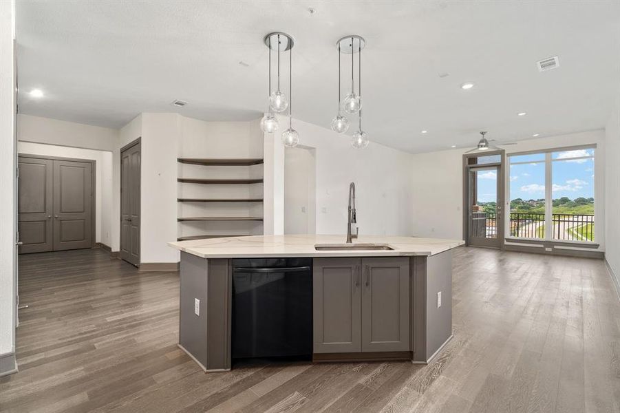 Kitchen featuring sink, black dishwasher, a center island with sink, light hardwood / wood-style flooring, and gray cabinetry