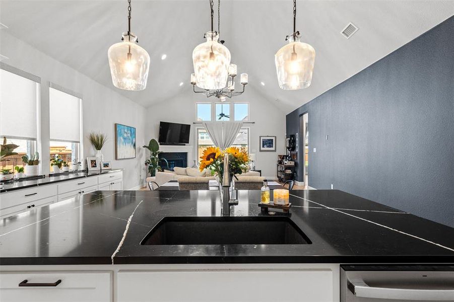 Kitchen featuring sink, dishwashing machine, white cabinets, and decorative light fixtures