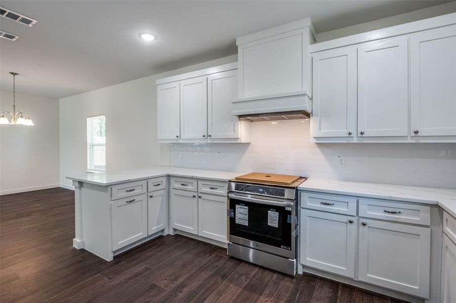 Kitchen featuring white cabinetry, dark wood-type flooring, and stainless steel range with electric cooktop