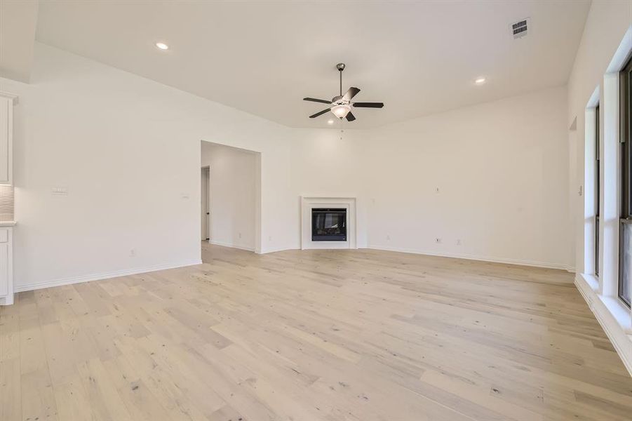 Unfurnished living room featuring light wood-type flooring and ceiling fan