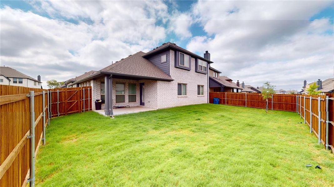 Back of house with a yard and a patio