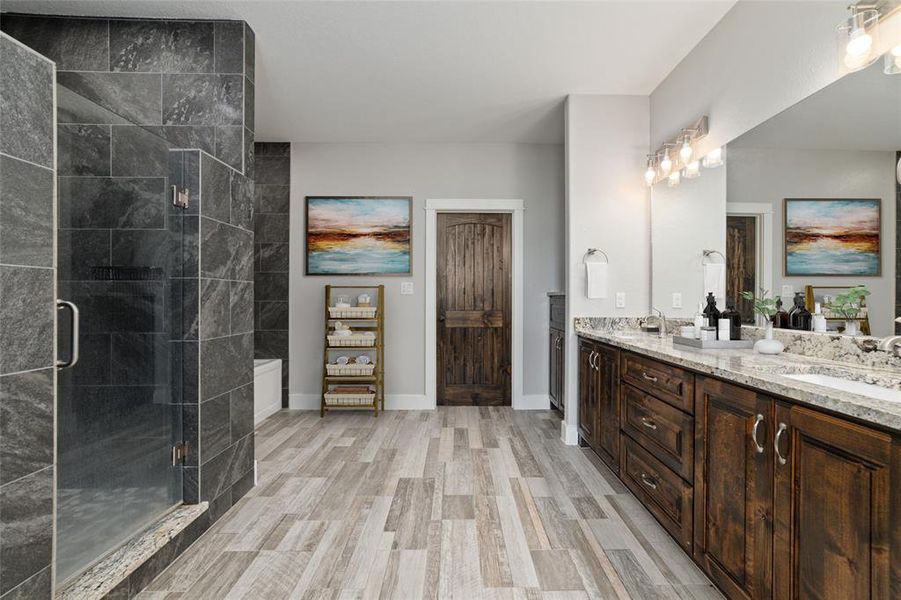 Virtually Staged. The luxurious primary bathroom, where rich dark wood cabinetry complements sleek tile flooring, and a generously sized oversized mirror spans the wall, adding a touch of elegance to your daily routine.