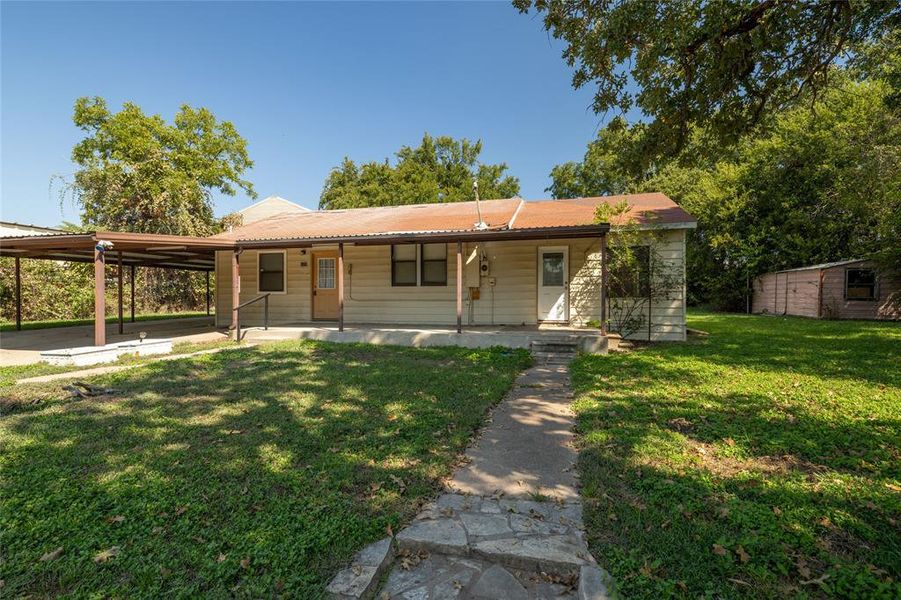 View of front facade featuring a porch, a carport, and a front yard