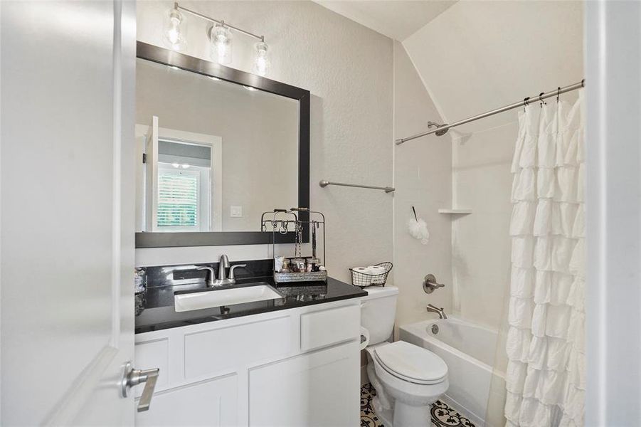 This full bathroom located upstairs offers beautiful tile flooring, a single sink vanity with a framed mirror and vanity lights above, an a fully tiled tub/shower enclosure.