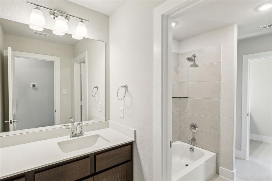 Bathroom with tiled shower / bath, vanity, and tile patterned floors