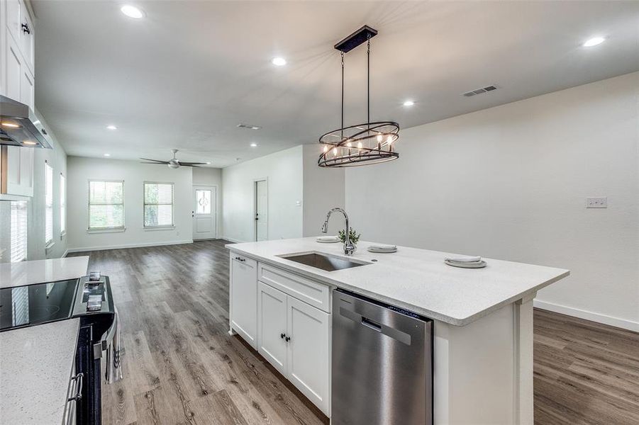 Kitchen featuring light hardwood / wood-style flooring, ceiling fan with notable chandelier, an island with sink, dishwasher, and sink