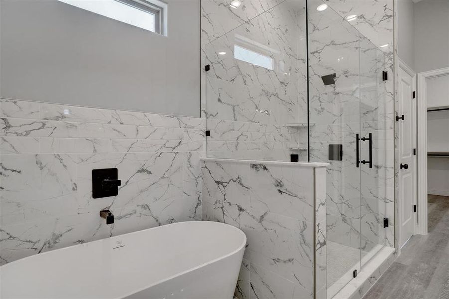 Bathroom featuring hardwood / wood-style floors, tile walls, and plus walk in shower