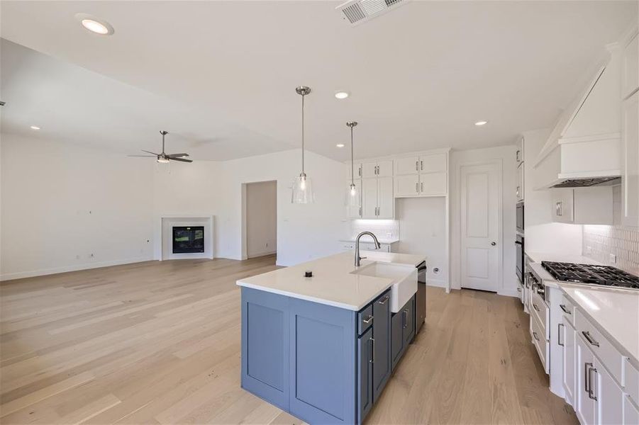 Kitchen featuring white cabinetry, light wood-type flooring, and pendant lighting