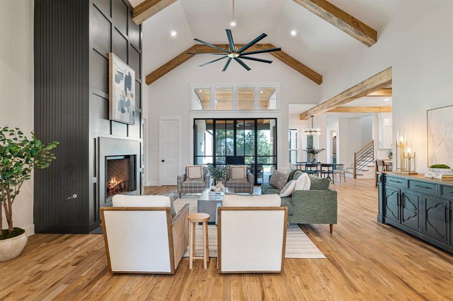 Living room featuring high vaulted ceiling, beam ceiling, ceiling fan, and light hardwood / wood-style floors