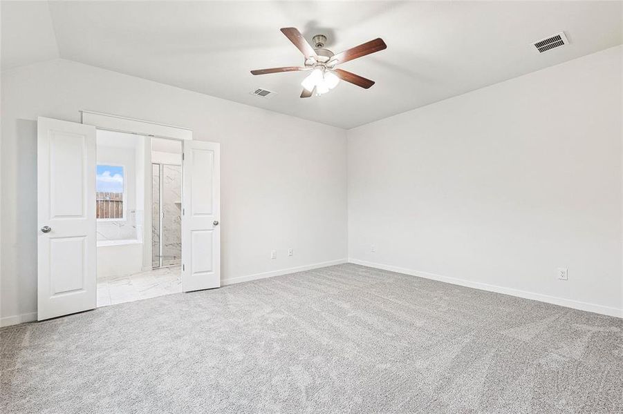 Unfurnished bedroom with connected bathroom, ceiling fan, lofted ceiling, and light colored carpet