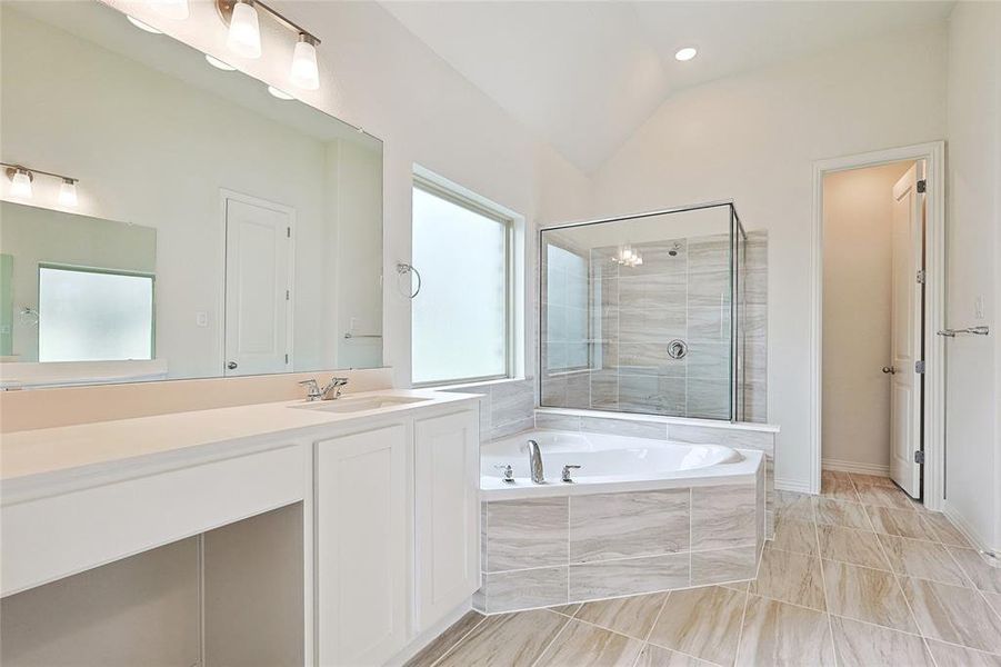 Bathroom featuring vanity, lofted ceiling, and shower with separate bathtub