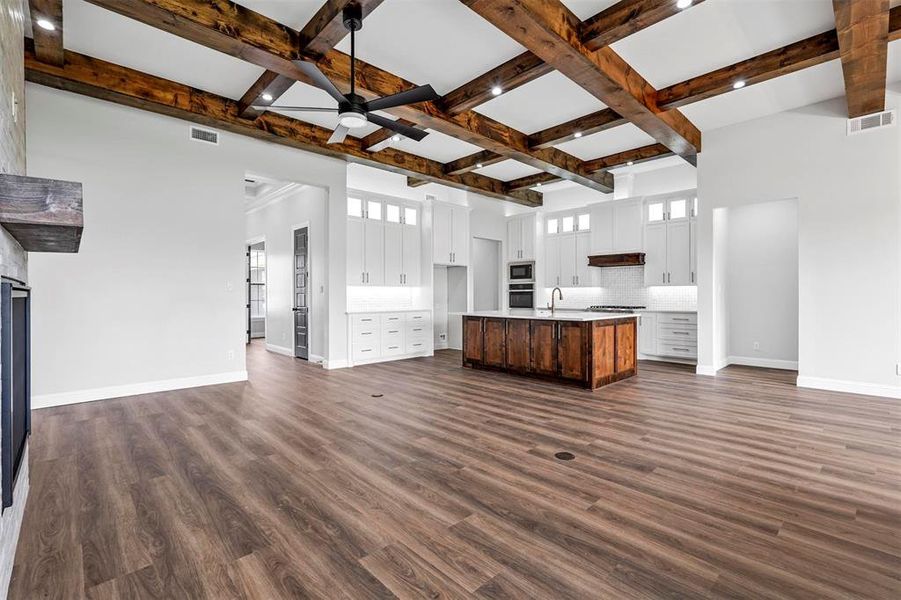 Unfurnished living room with a healthy amount of sunlight, dark hardwood / wood-style floors, ceiling fan, and coffered ceiling
