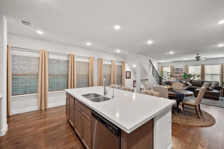 Kitchen with hardwood / wood-style floors, dishwasher, an island with sink, and sink