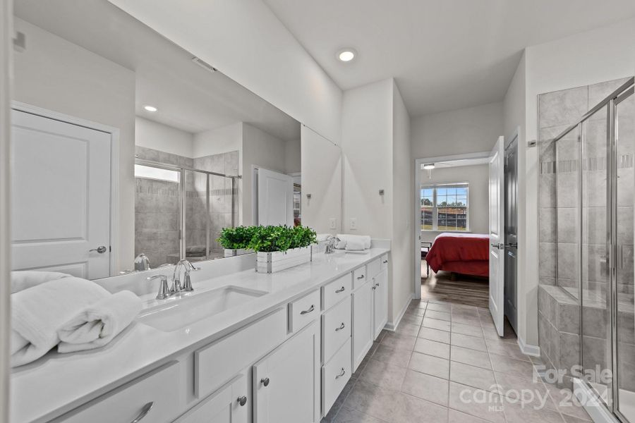 Primary En Suite Bath includes sprawling two station vanity, extra large tiled shower area with seat, private toilette, and walk in closet. situated off the primary bedroom.