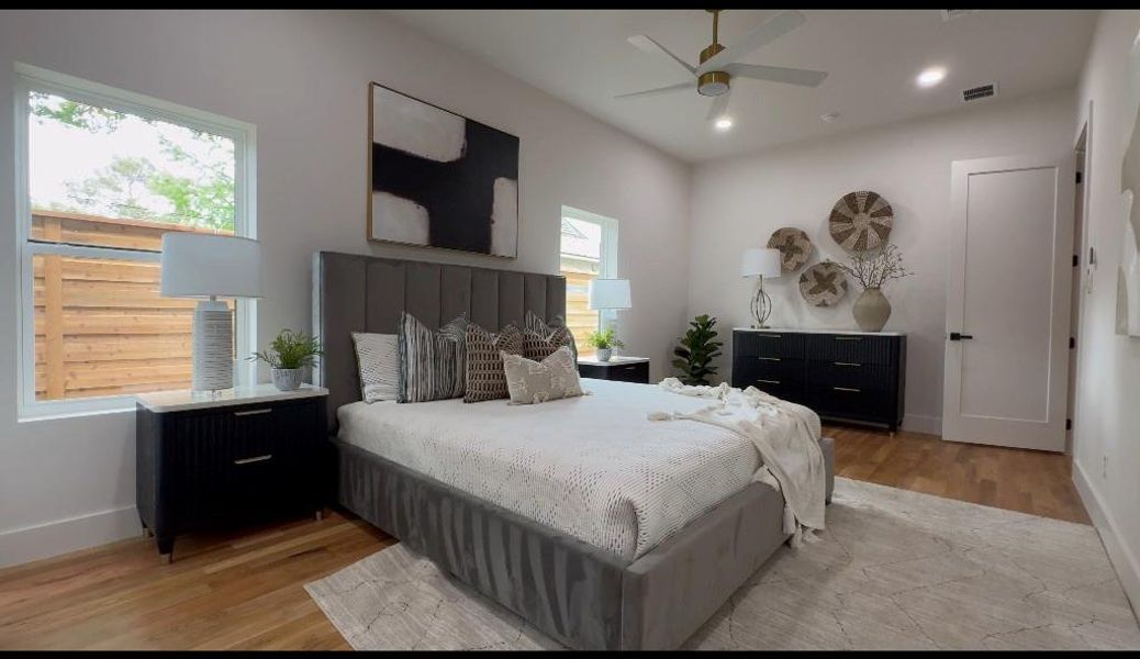 Bedroom featuring ceiling fan, multiple windows, and light hardwood / wood-style flooring