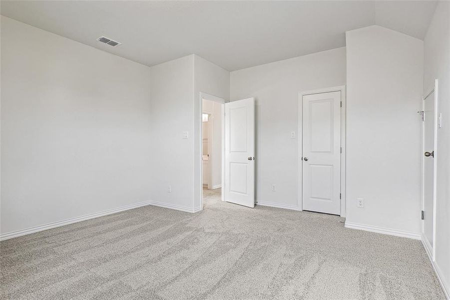 Unfurnished bedroom featuring lofted ceiling and light colored carpet