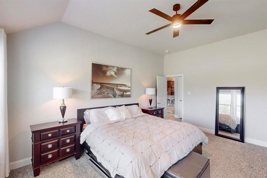 Bedroom with light colored carpet, vaulted ceiling, and ceiling fan