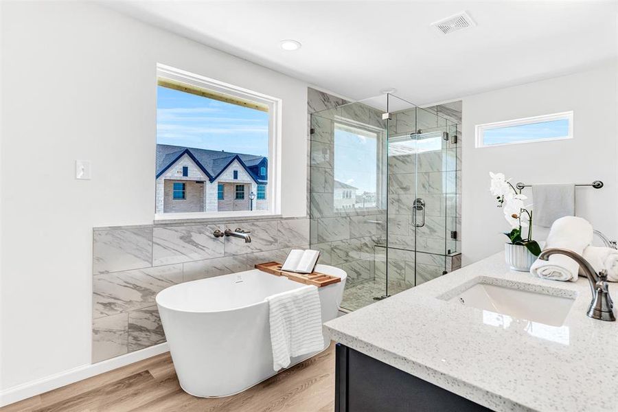 Bathroom featuring hardwood / wood-style flooring, separate shower and tub, vanity, and plenty of natural light