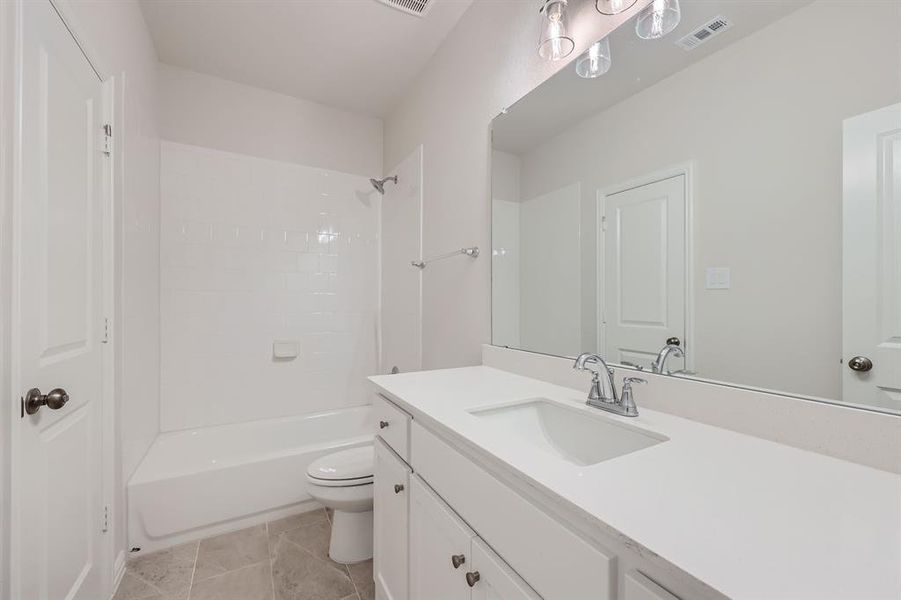 Full bathroom with vanity, toilet, tile patterned floors, and tiled shower / bath