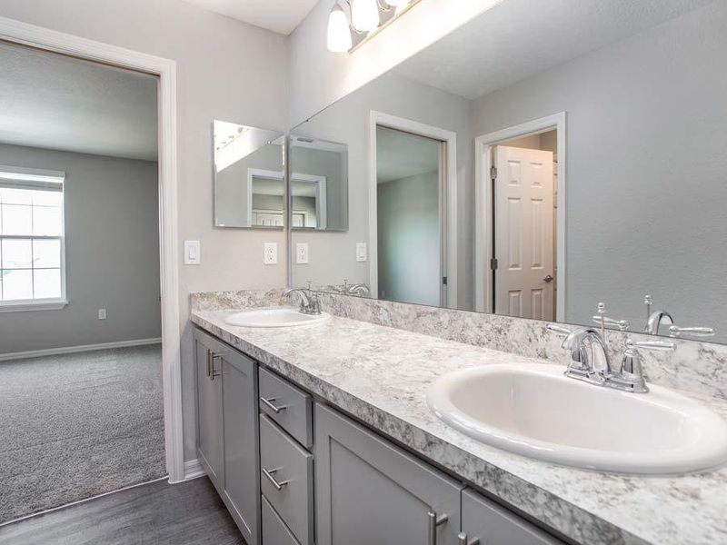 Jack-and-Jill bathroom with dual vanities, a linen closet, and enclosed tub and toilet area, with entries from bedrooms 3 and 4 - Westbrooke ll home plan by Highland Homes