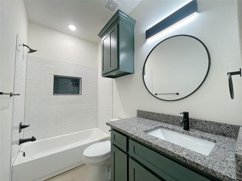 Full bathroom with vanity, tiled shower / bath, and toilet